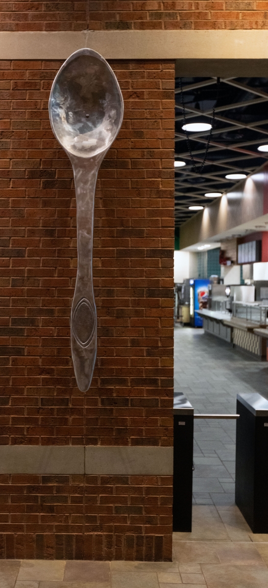 Image of metal spoon sculpture hanging on wall of dining hall