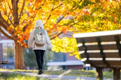 Image of student walking through campus during Fall
