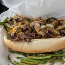Shaved Ribeye with grilled veggies in a sub-style bun with grilled green beans on the side